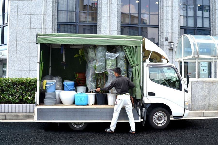 植物を積んだ専用トラックと担当者
